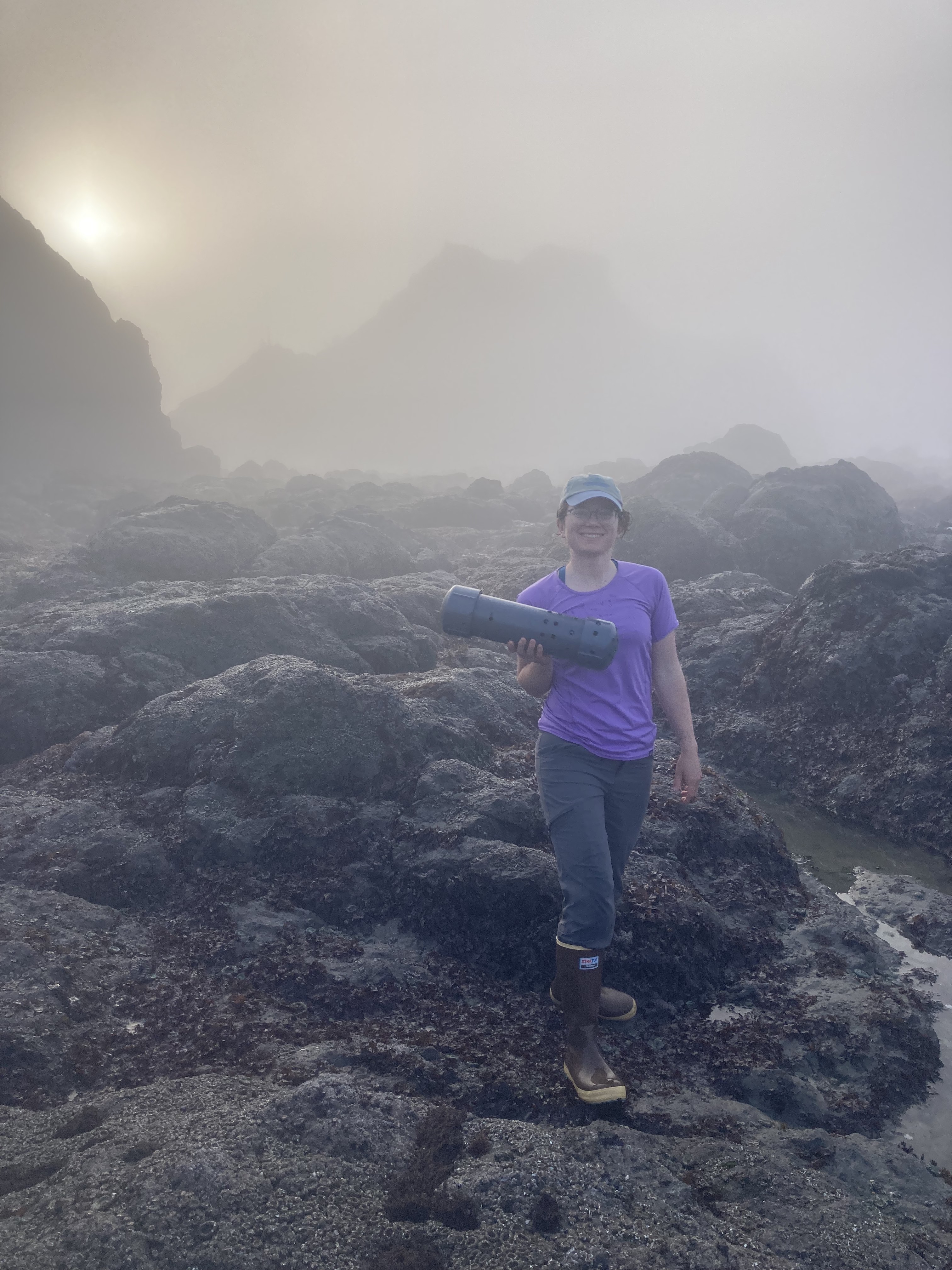 Amelia holding a pH sensor housing in the rocky intertidal zone on a foggy morning.